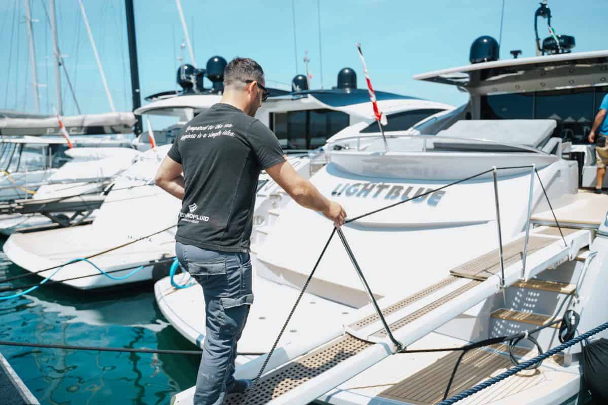 Uomo che si prepara a salire su un motoscafo di lusso in porto.